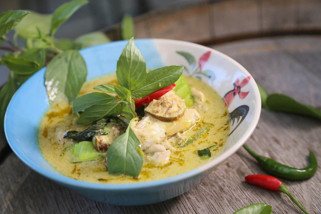 Thai green curry in a colourful bowl with Thai basil leaves